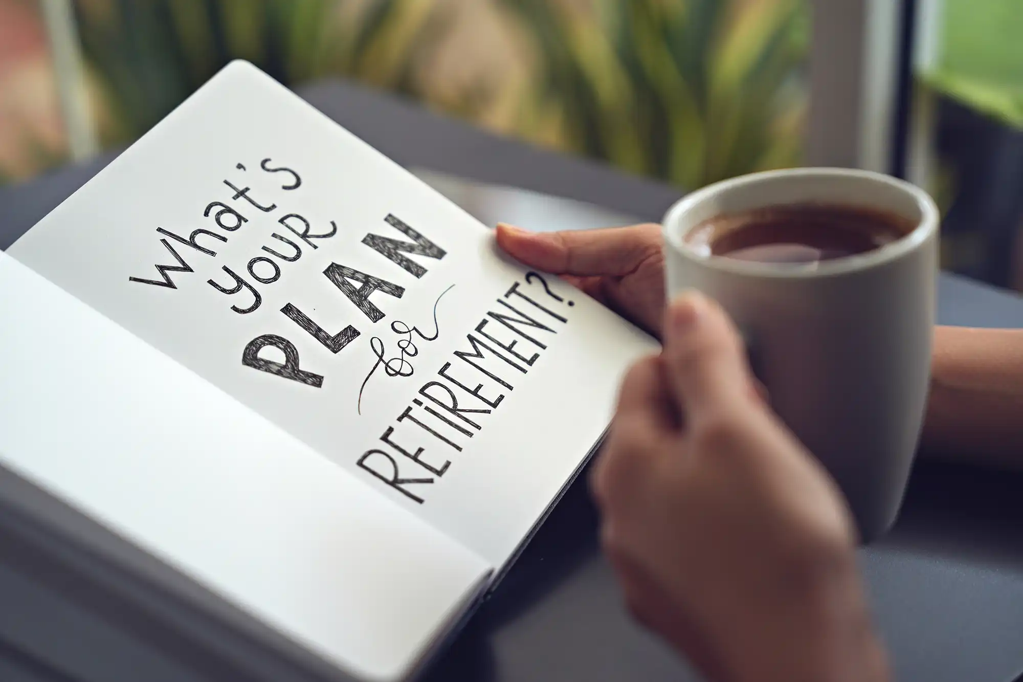 Person's hands holding cup of tea and book